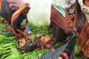 Baggage off: A woman opens her noken, a traditional Papuan woven bag, filled with sweet potatoes next to the cooking pit, while other women bring their noken closer to the pit.