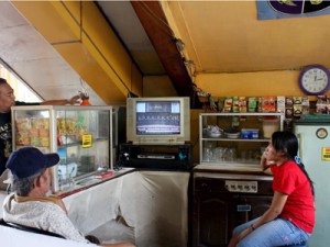 Pervasive medium: Three people watch a television program in a shop at a railway station in Jakarta. Activists argue that many religious TV programs play a symbolic rather than a substantial role in religion, and tend to marginalize minority groups. JP/Nurhayati